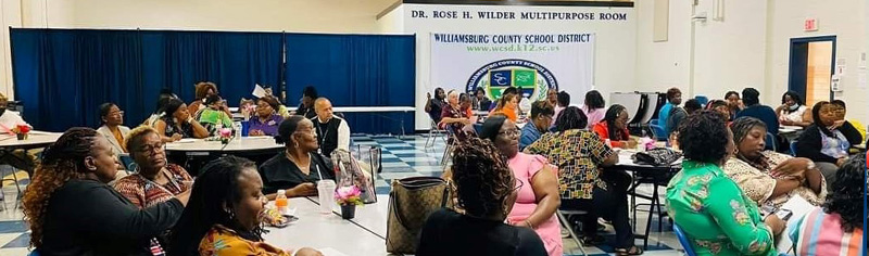 Groups of primarily black female educators sitting at tables in the Dr. Rose H Wilder Mulipurfose Room